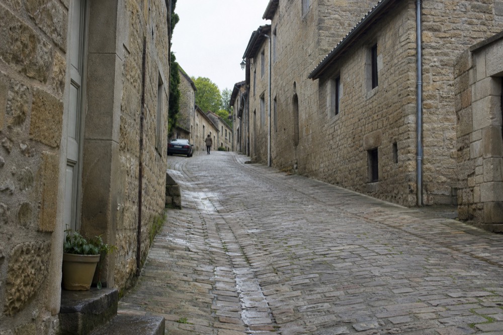 Narrow cobbled medieval lane in Saint-Emilion with honey-stone buildings, no text, no logos, no people.