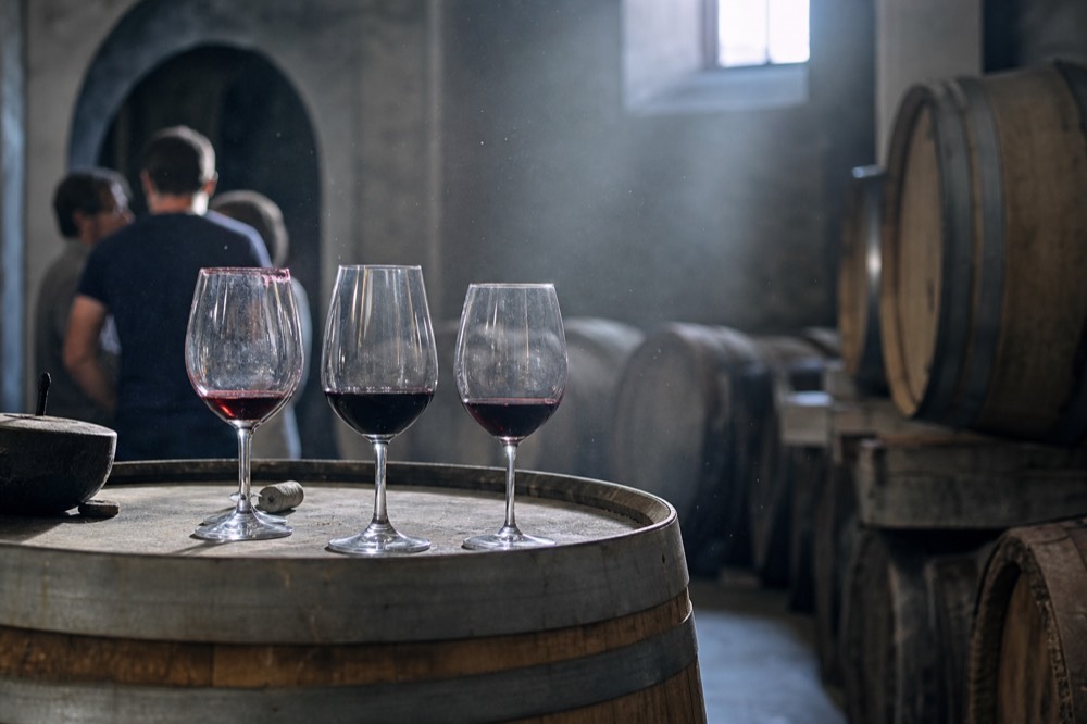 A tasting room with glasses of red wine on a barrel top, no text, no logos, no people