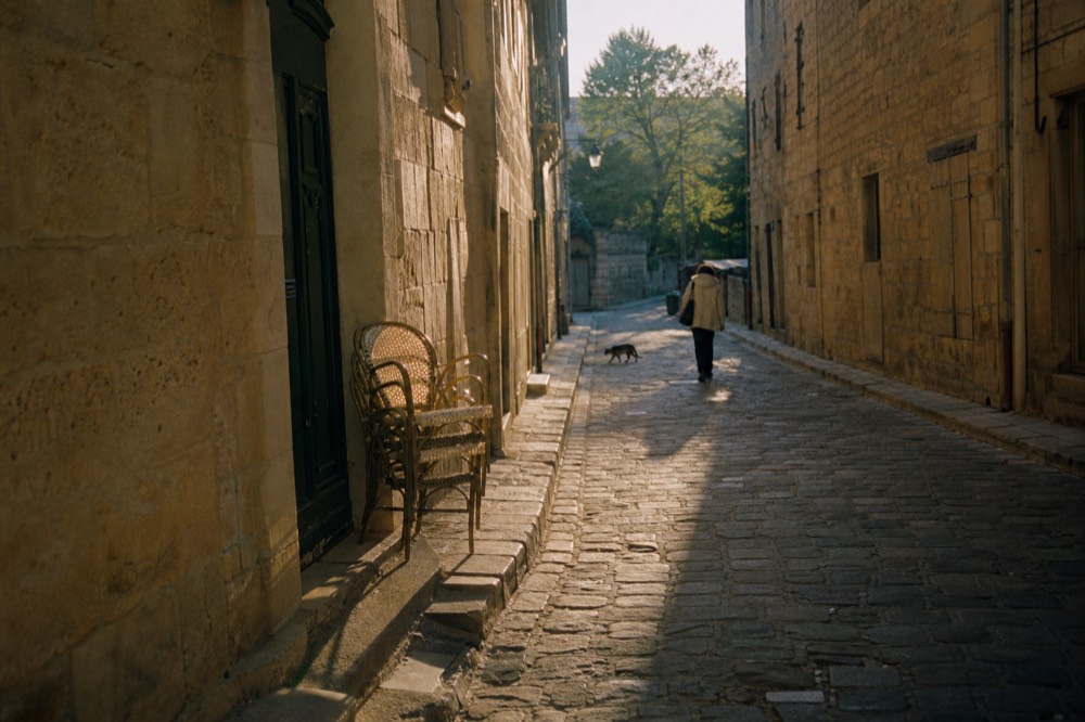 Cobblestone lane between golden stone buildings in Saint-Emilion old town in early morning light, no text, no logos, no people