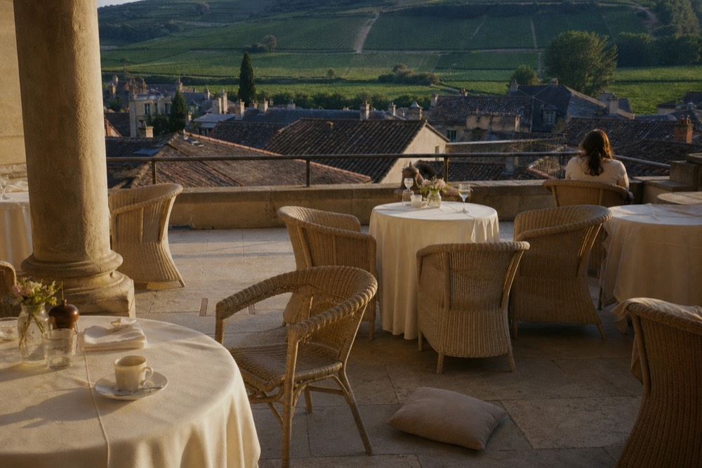 Hotel terrace overlooking vineyards beyond the rooftops of Saint-Emilion village, no text, no logos, no people